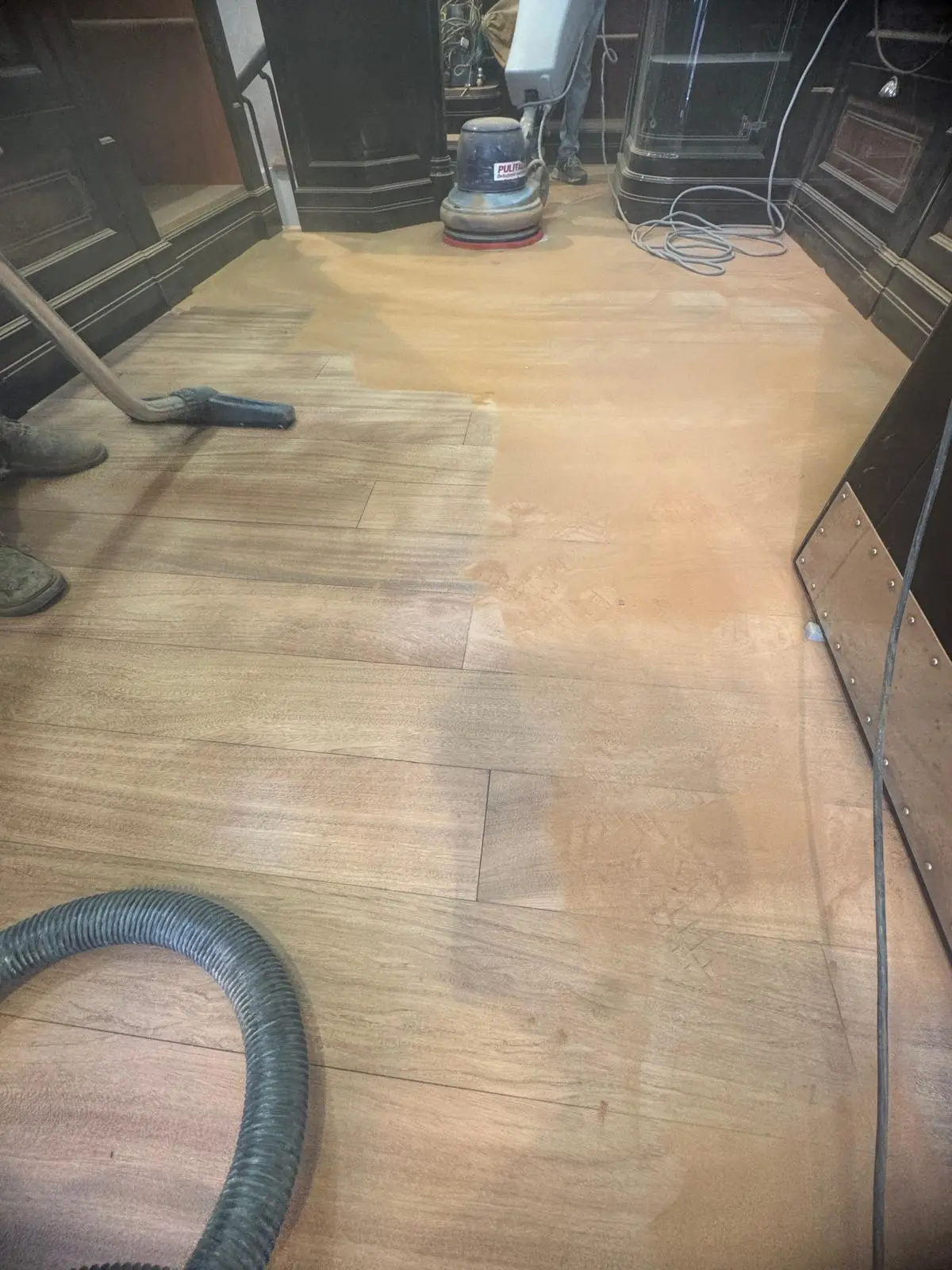 Levigatura di parquet scuro con aspiratore e monospazzola in salone con camino