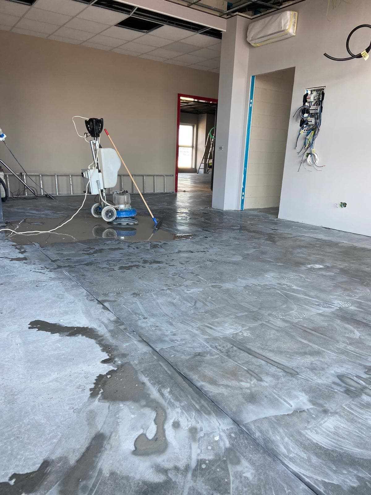 Monospazzola professionale al lavoro su pavimento in cemento in locale commerciale in ristrutturazione