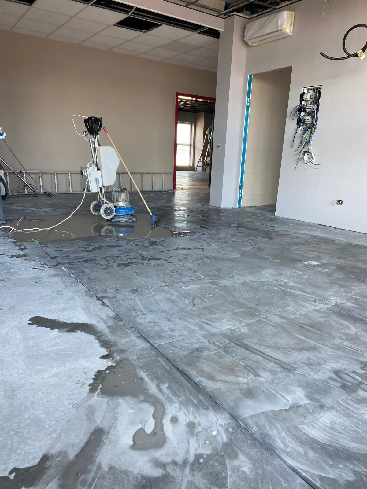Monospazzola professionale al lavoro su pavimento in cemento in locale commerciale in ristrutturazione