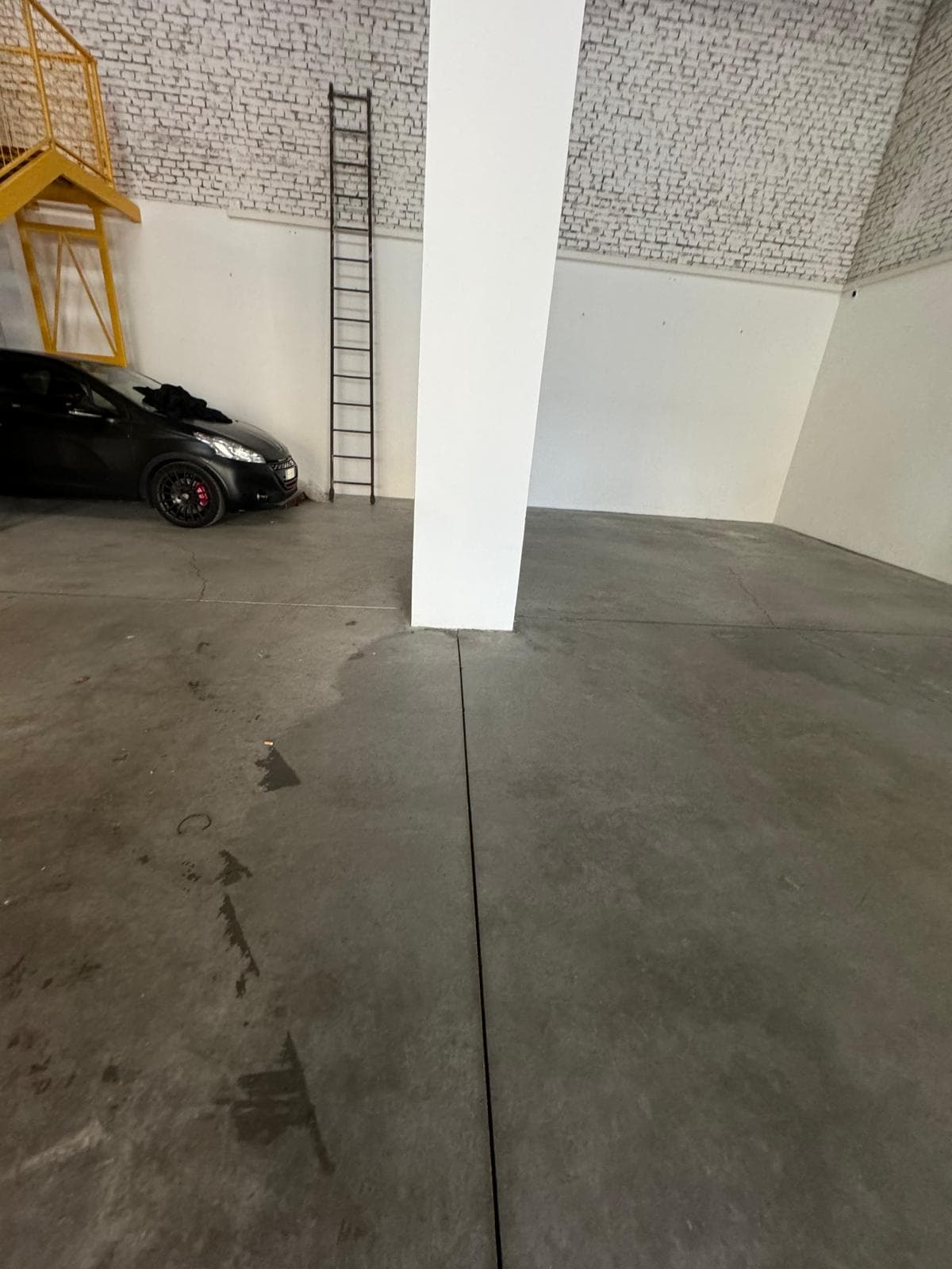 Pulizia di un garage privato con pavimento in cemento e auto parcheggiata