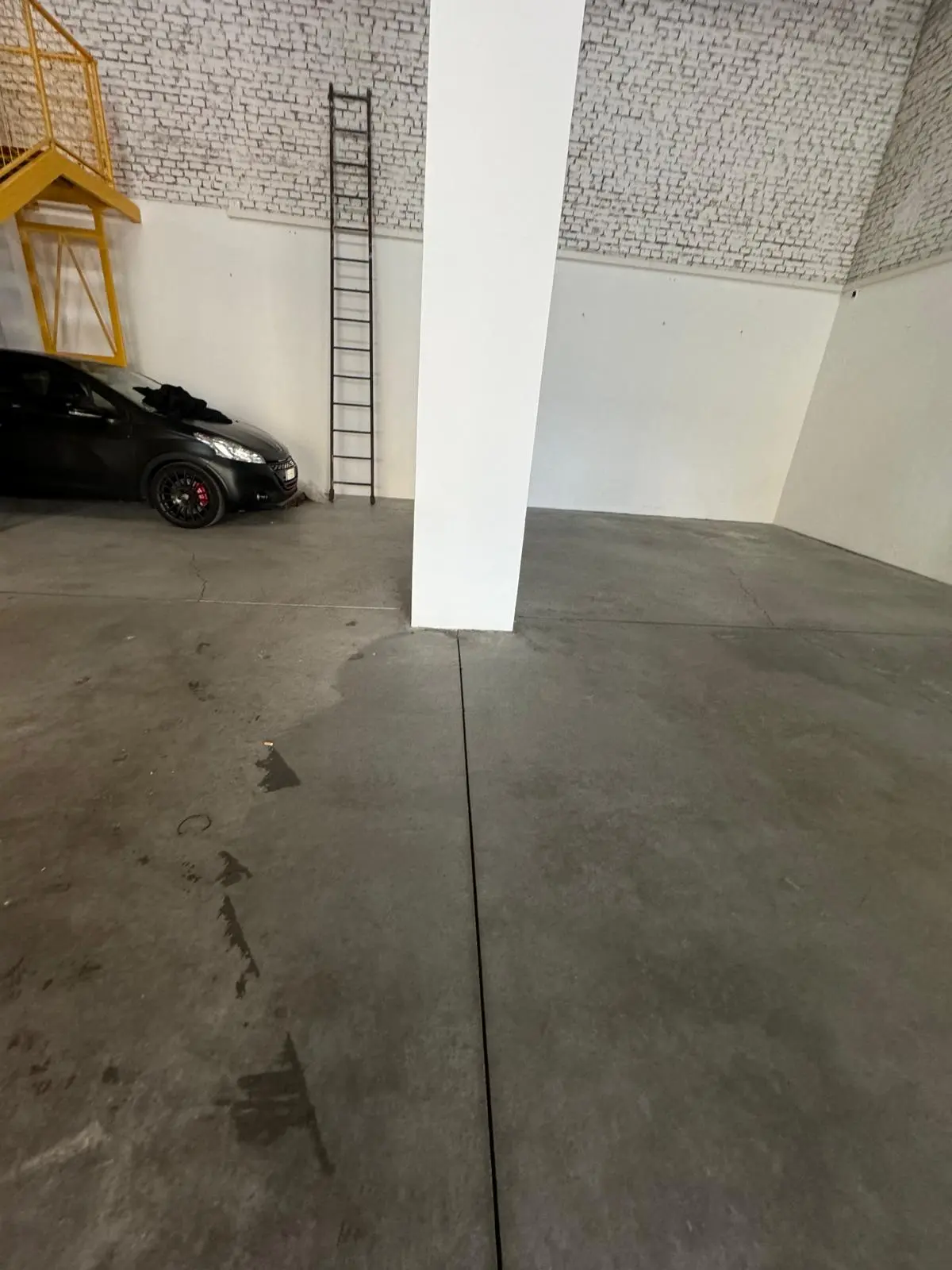 Pulizia di un garage privato con pavimento in cemento e auto parcheggiata