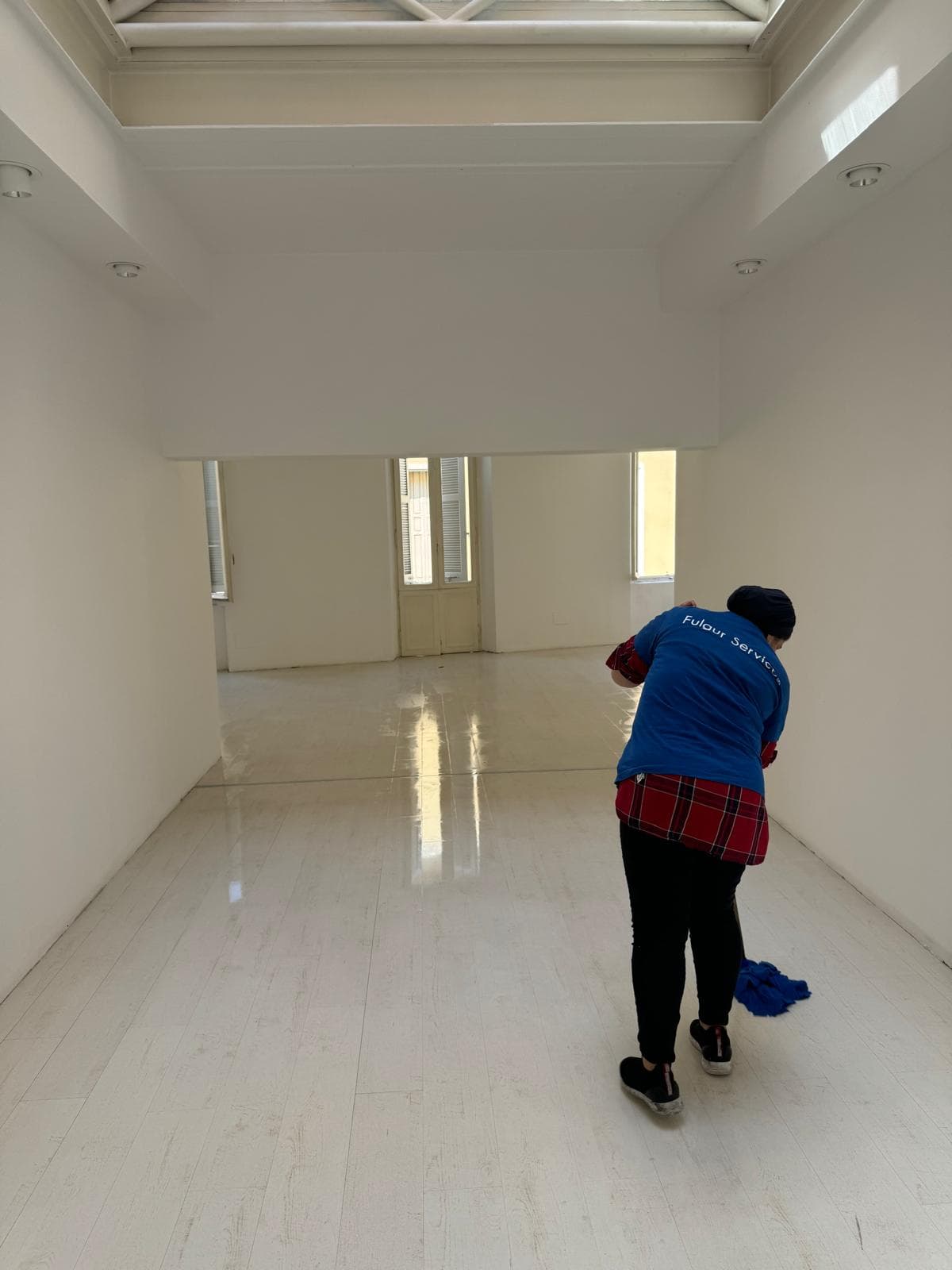 Operatore Fulgur Service su scala pulisce scaffalature metalliche in magazzino