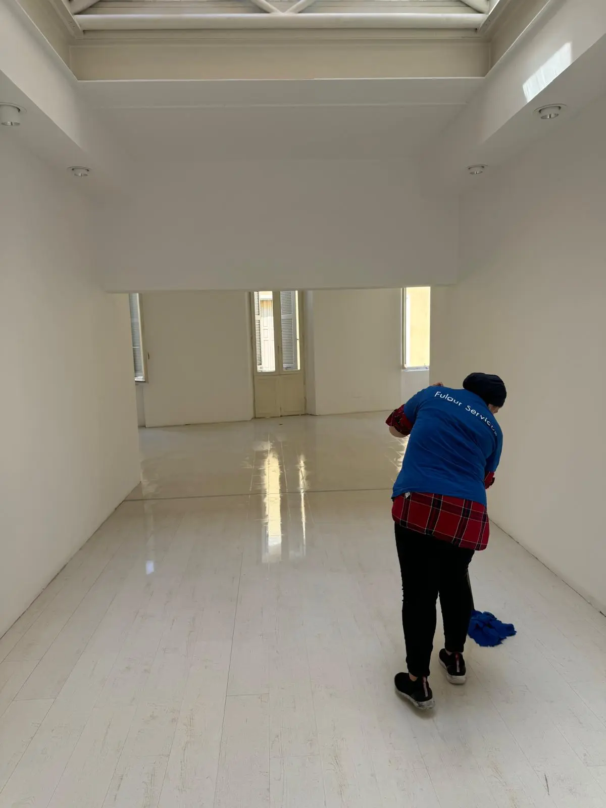 Operatore Fulgur Service su scala pulisce scaffalature metalliche in magazzino