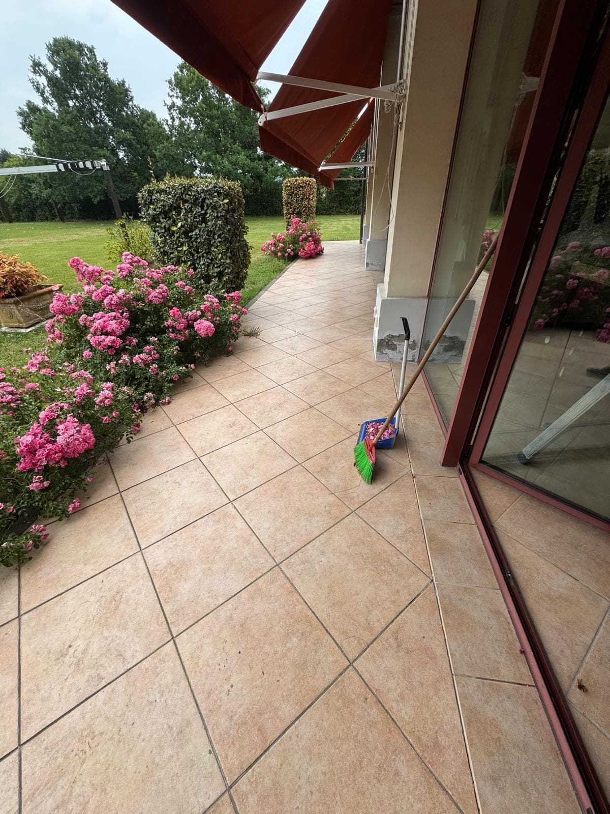 Pulizia di terrazzo residenziale con pavimento in gres e giardino fiorito con rose