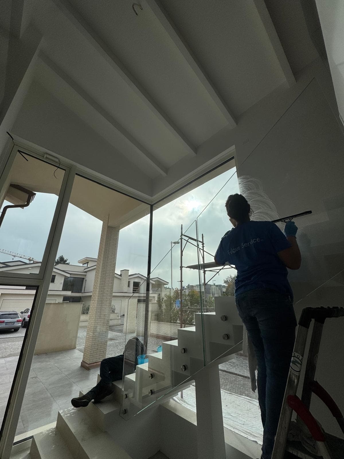 Operatore pulisce vetrate e vetro strutturale su scala moderna di villa privata