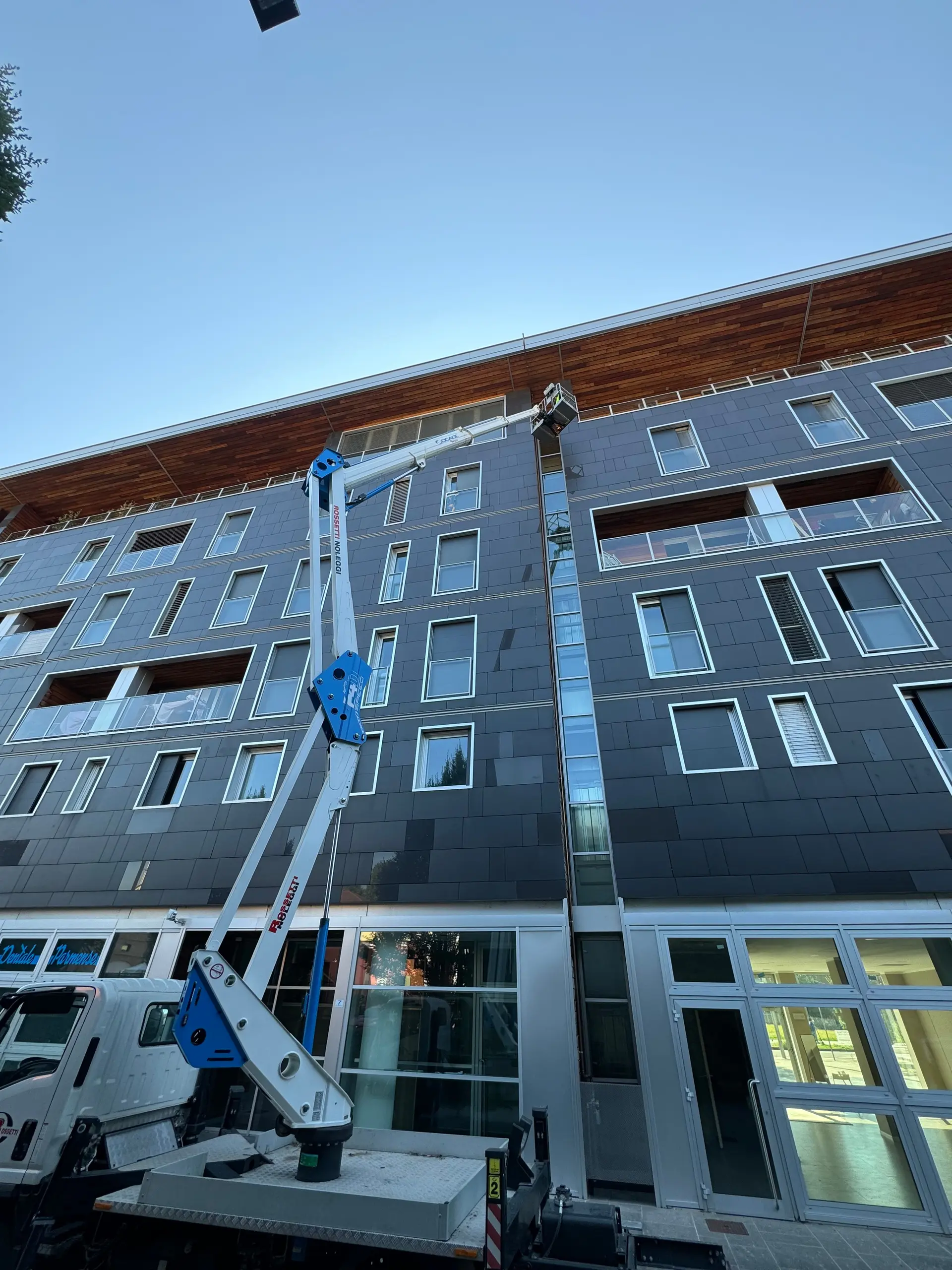 Operatore esperto su piattaforma aerea mentre esegue il lavaggio di una facciata vetrata continua in quota