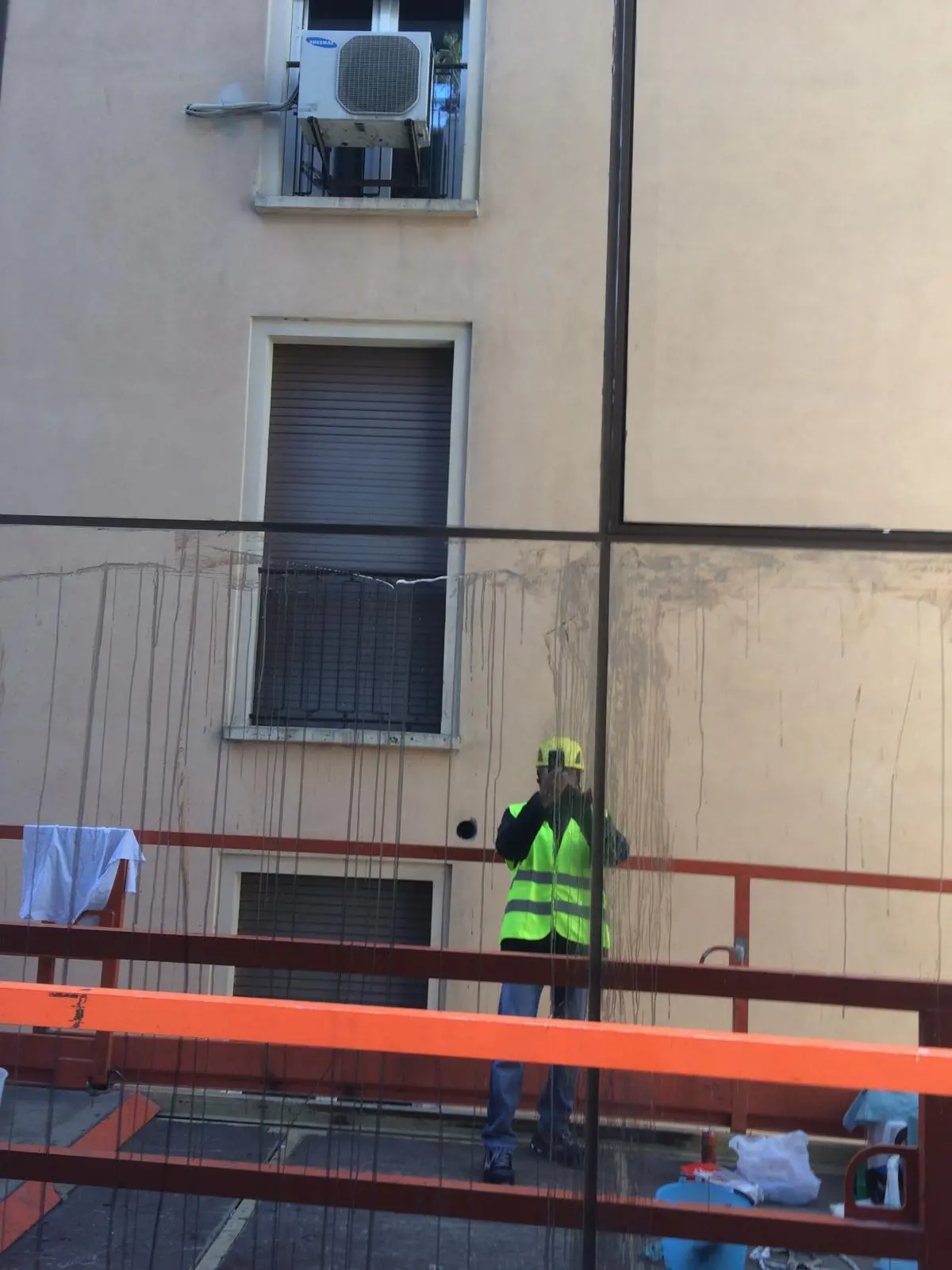 Operatore con gilet catarifrangente su ponteggio per pulizia di facciata edificio urbano