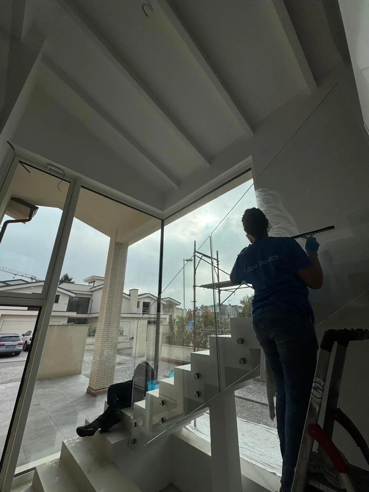 Operatore pulisce vetrate e vetro strutturale su scala moderna di villa privata